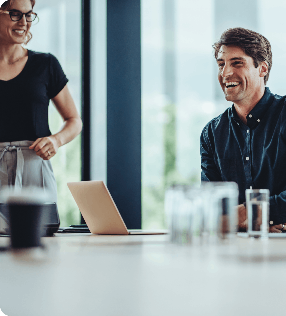 A man and woman smiling while collaborating in a modern office space