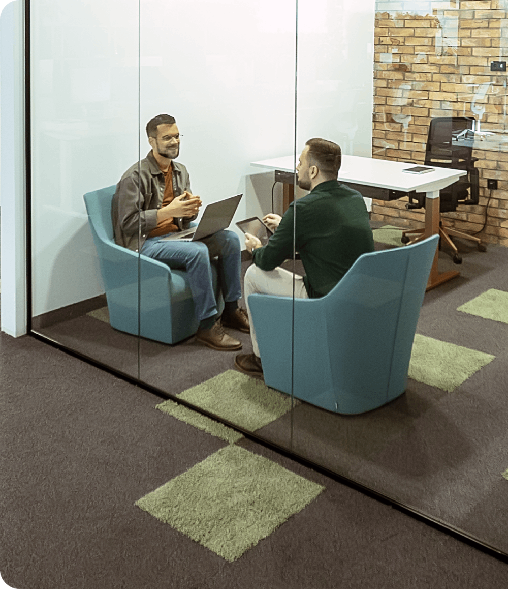 Two professionals sitting in a modern glass meeting room having a discussion
