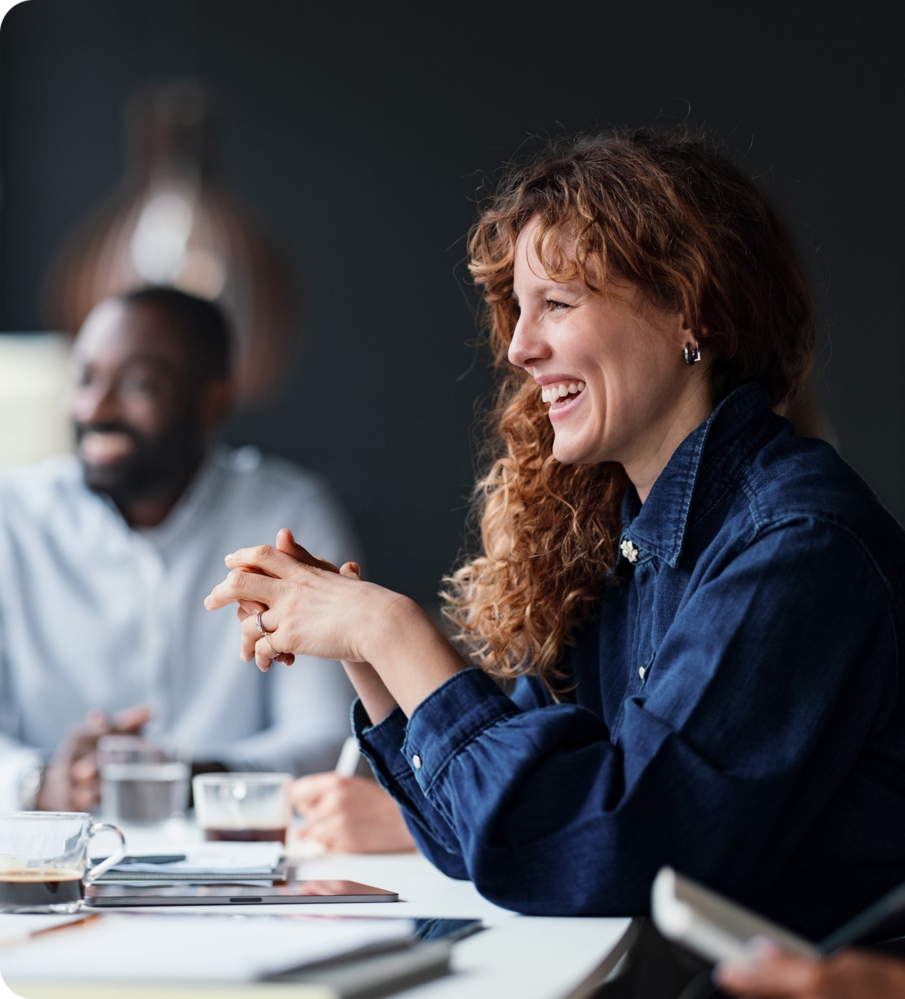 A smiling woman discussing work with a colleague in a bright, modern office space