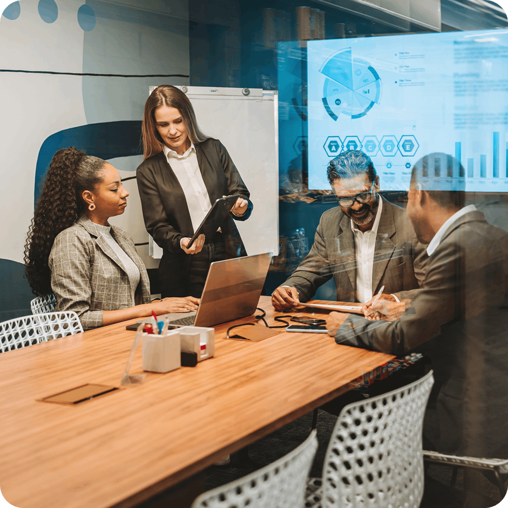 Modern collaborative office workspace with professionals sitting around a wooden table in a meeting Modern collaborative office workspace with professionals sitting around a wooden table in a meeting