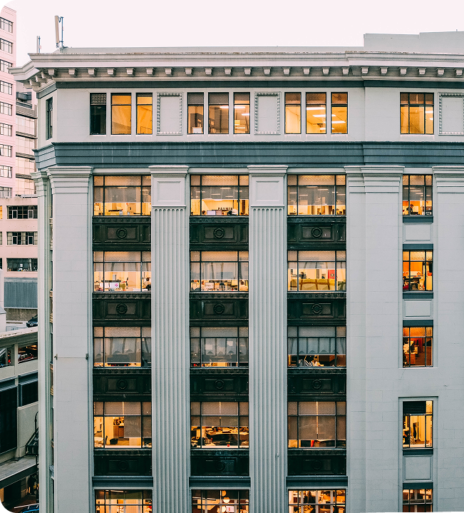 Modern multi-story office building exterior with illuminated windows during twilight